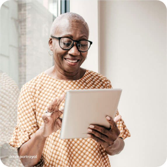 Woman on iPad smiling reflects patients & caregivers using Acadia Connect™ free insurance coverage tool for prescriptions