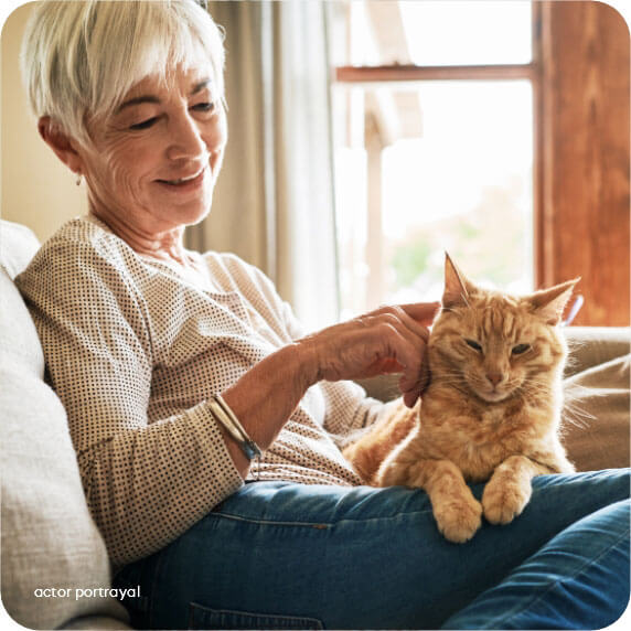 Actor portrayal of a woman sitting on her couch and petting her cat