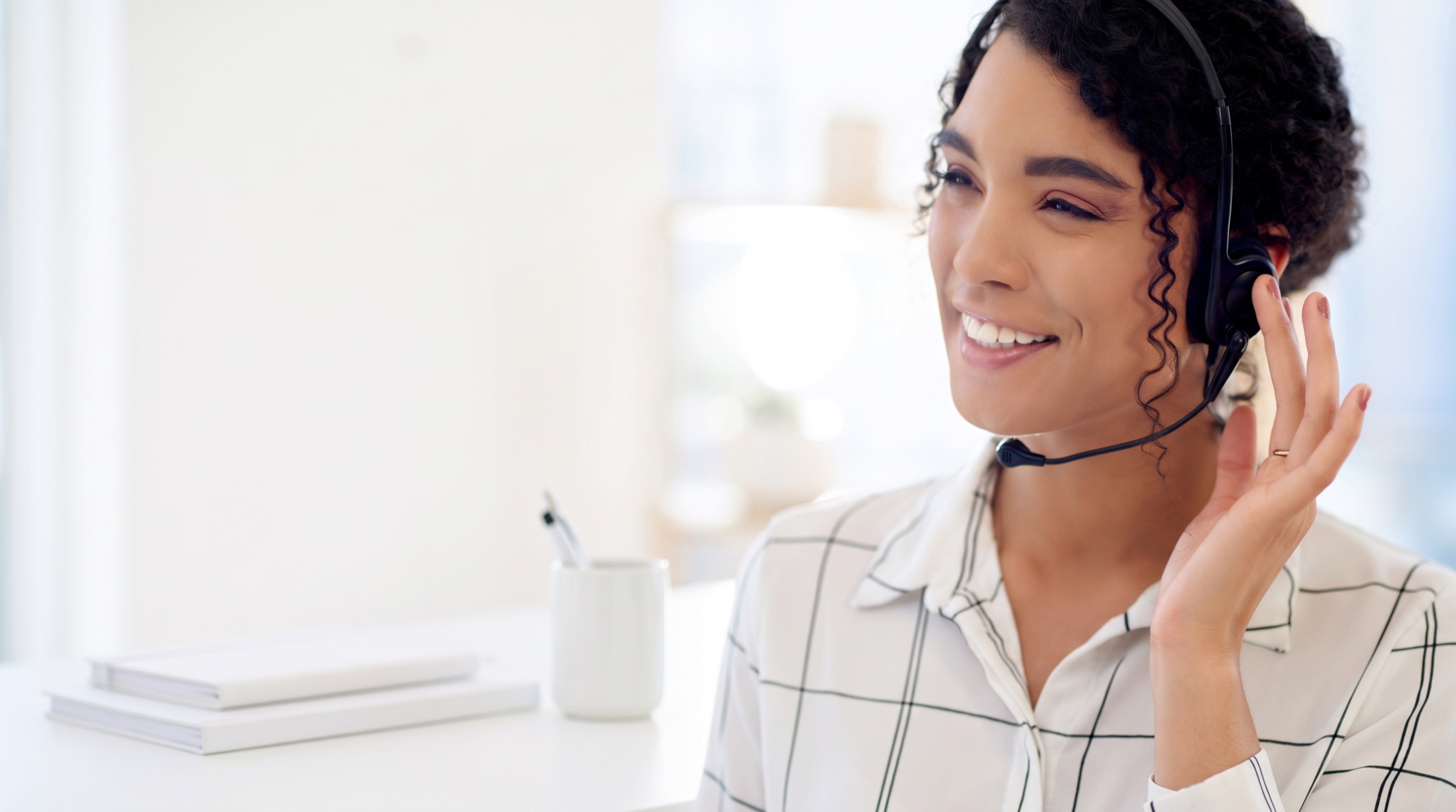 Three-quarter profile of a woman talking on a headset, one hand raised, in an office, next to copy describing Acadia Connect®